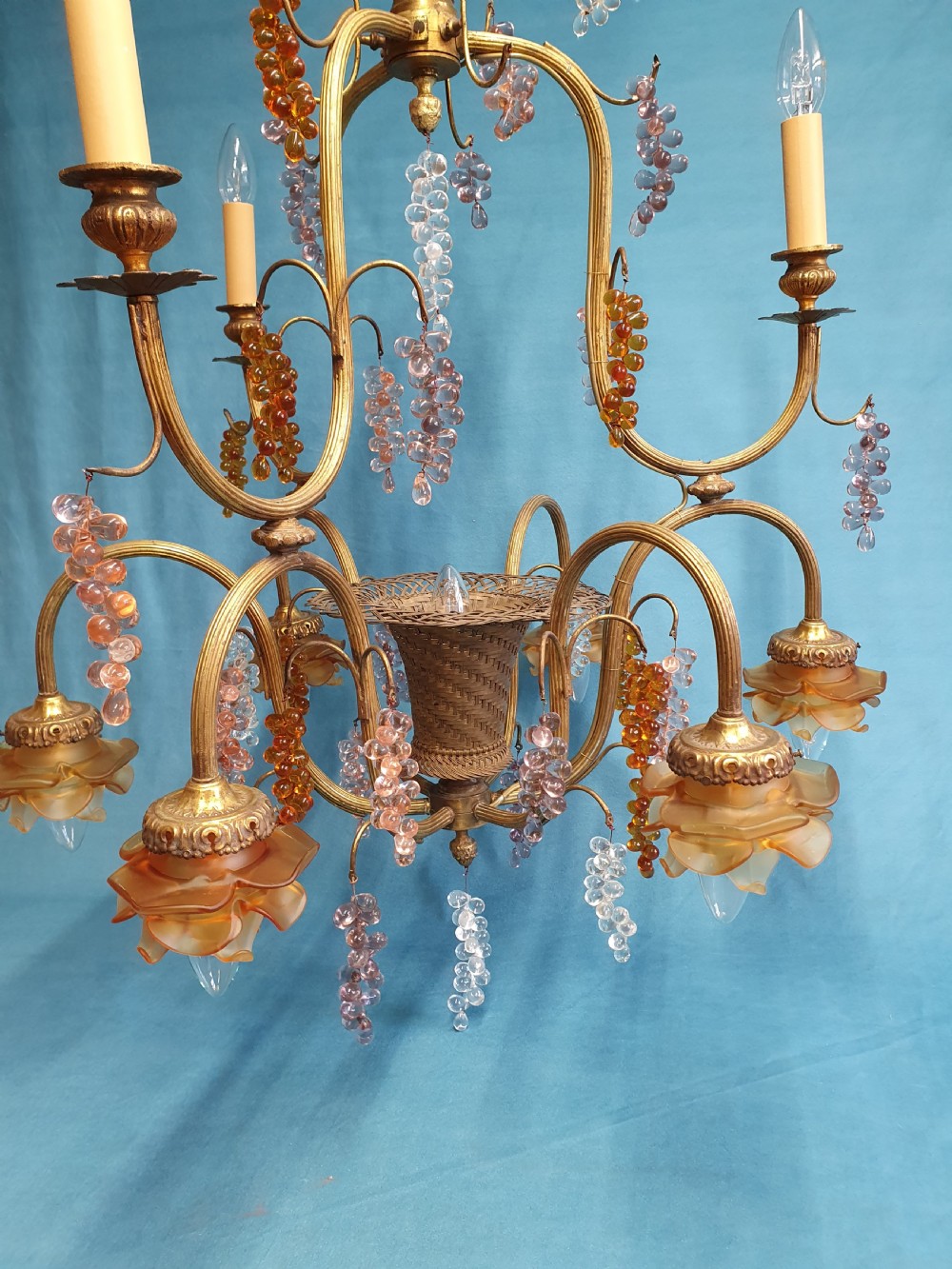 A French brass chandelier adorned with multi-coloured glass grape clusters, scrollwork arms, floral glass cups, and white lampshades. View VIII
