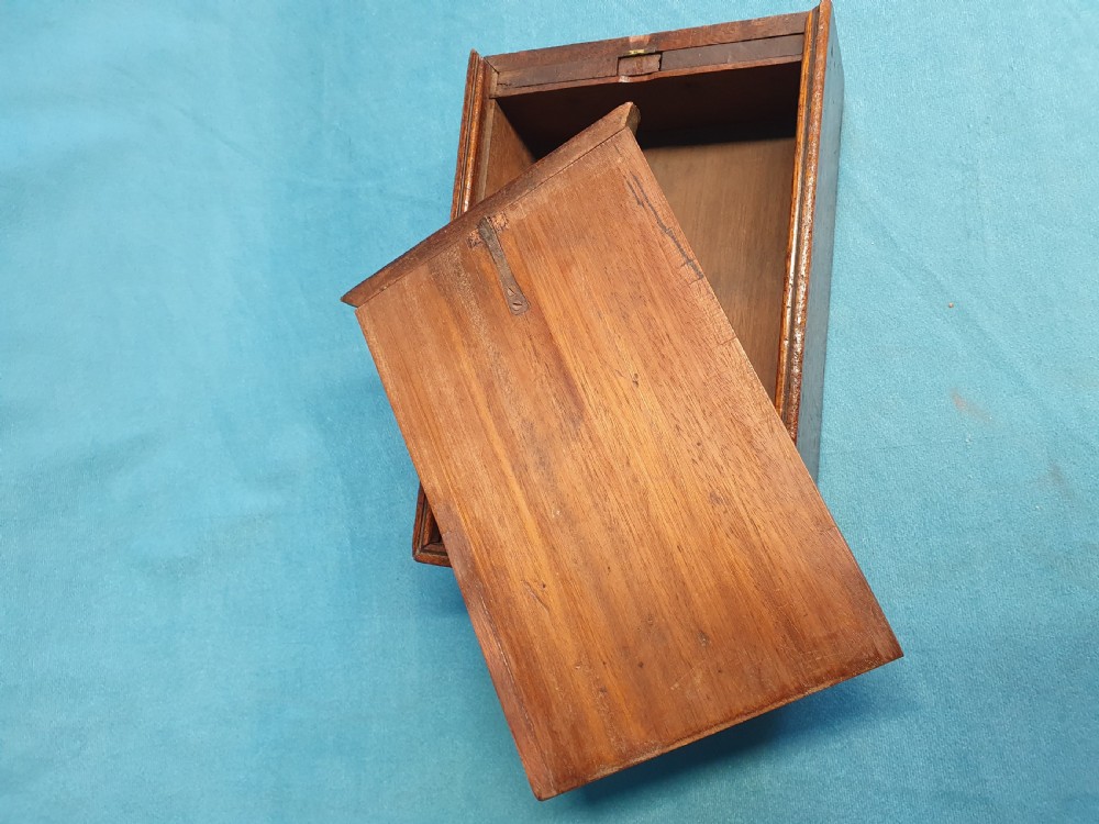 Close-up view of a small open mahogany box with a wooden spring catch mechanism along the rim. View II
