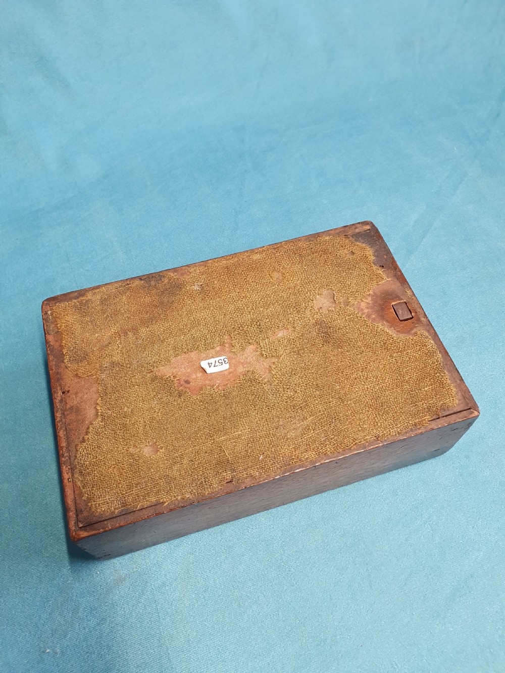 Close-up view of a small open mahogany box with a wooden spring catch mechanism along the rim. View III
