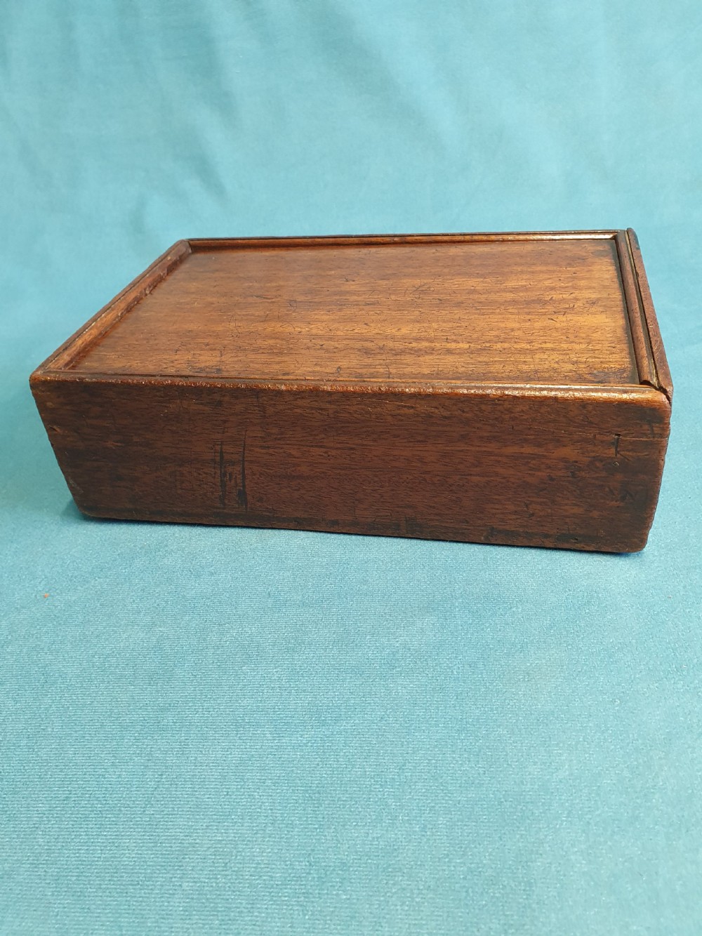 Close-up view of a small open mahogany box with a wooden spring catch mechanism along the rim. View V
