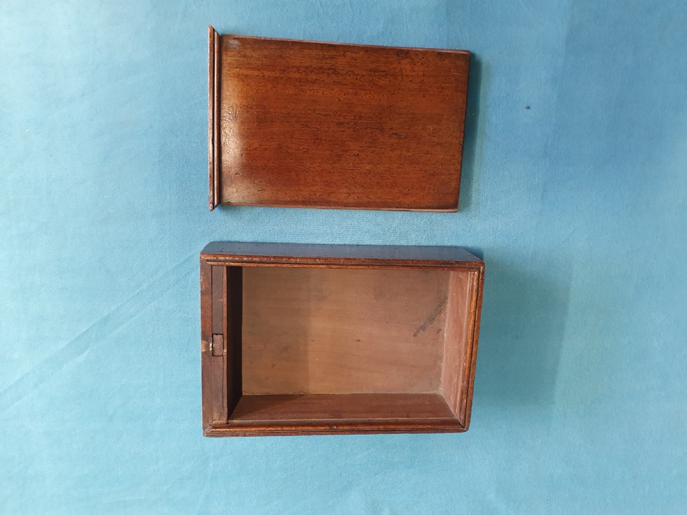 Close-up view of a small open mahogany box with a wooden spring catch mechanism along the rim. View VI