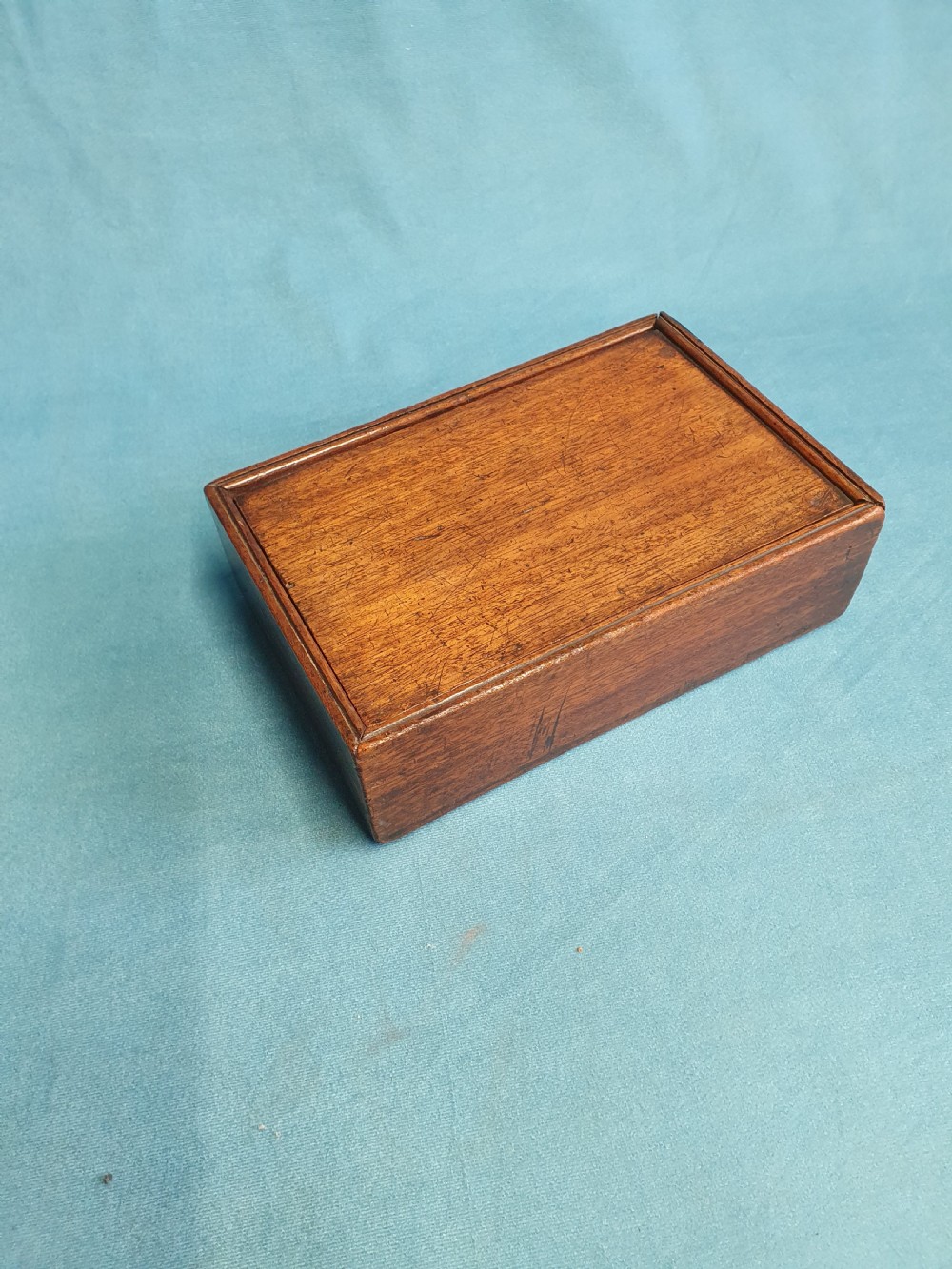 Close-up view of a small open mahogany box with a wooden spring catch mechanism along the rim. View VII