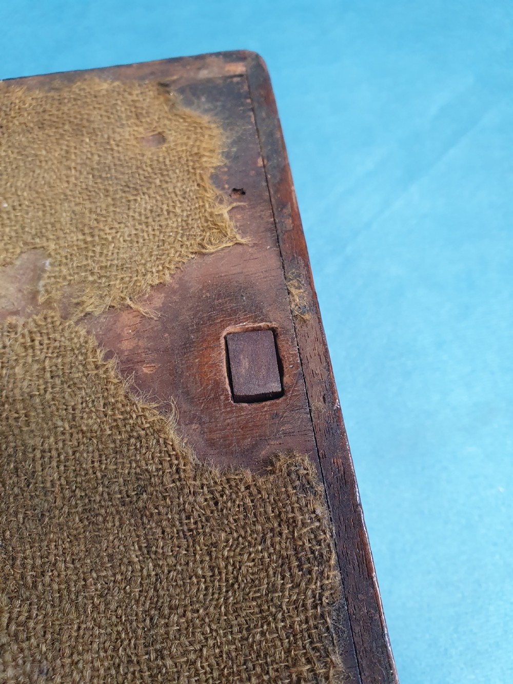 Close-up view of a small open mahogany box with a wooden spring catch mechanism along the rim. View VIII