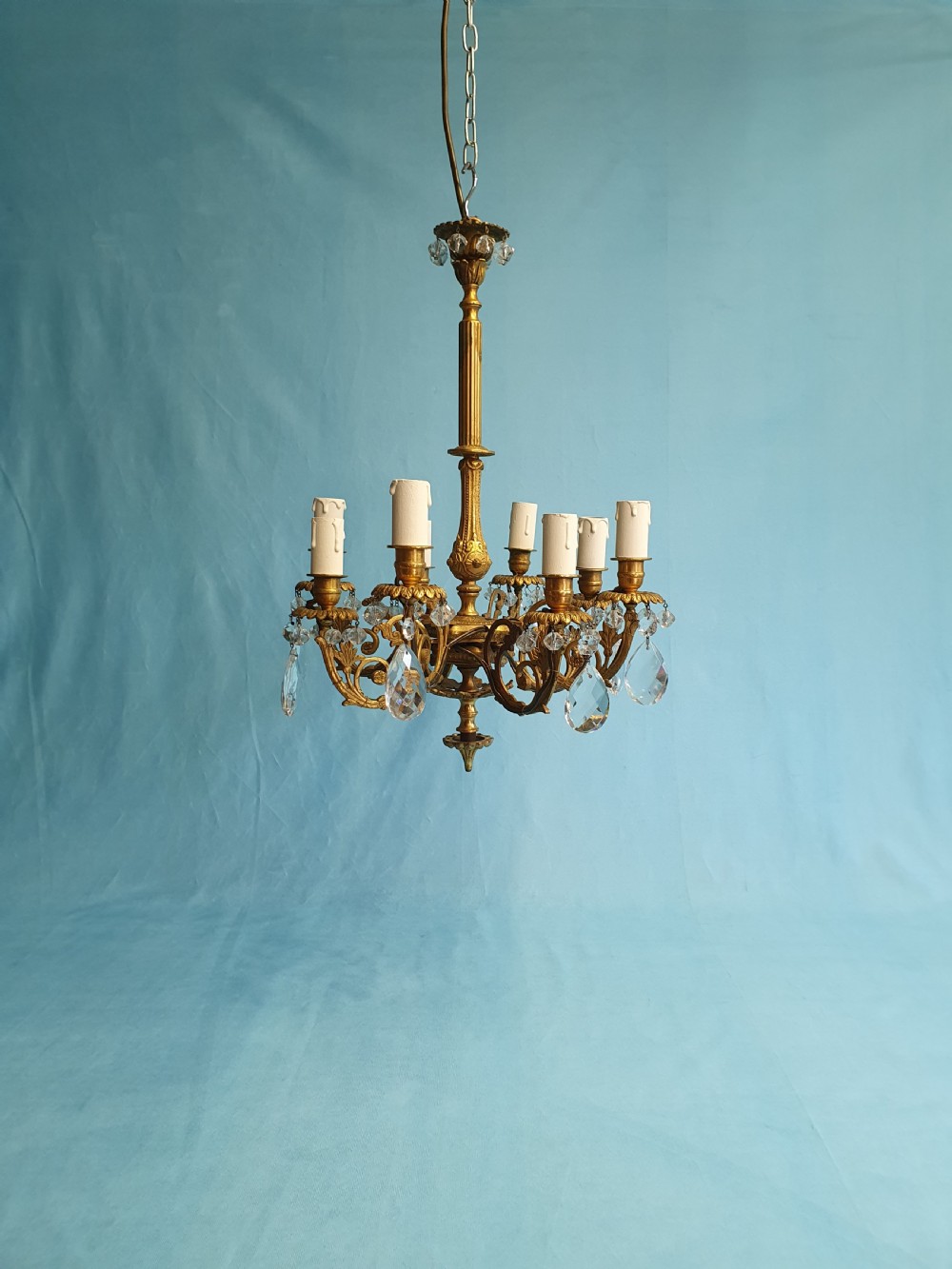 An eight-arm brass ceiling chandelier featuring candle-effect light fittings and suspended crystal glass drops.