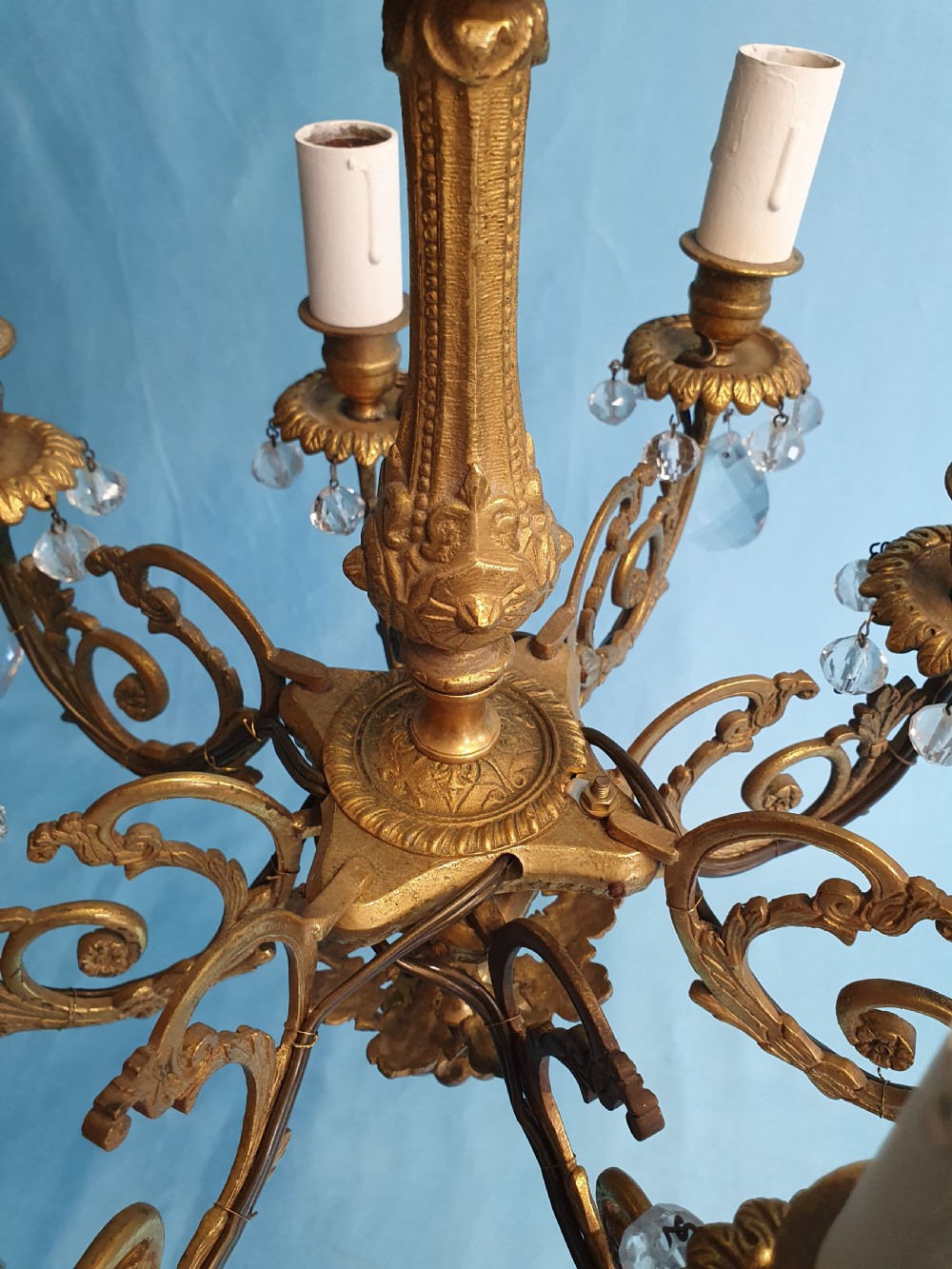 An eight-arm brass ceiling chandelier featuring candle-effect light fittings and suspended crystal glass drops. View IV