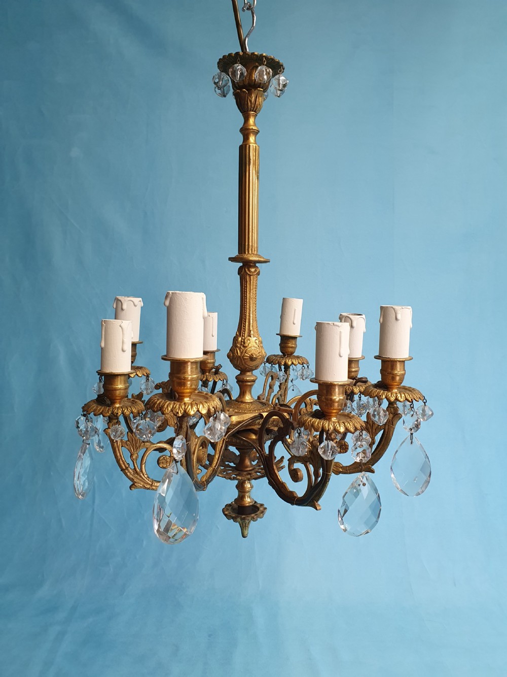 An eight-arm brass ceiling chandelier featuring candle-effect light fittings and suspended crystal glass drops. View V