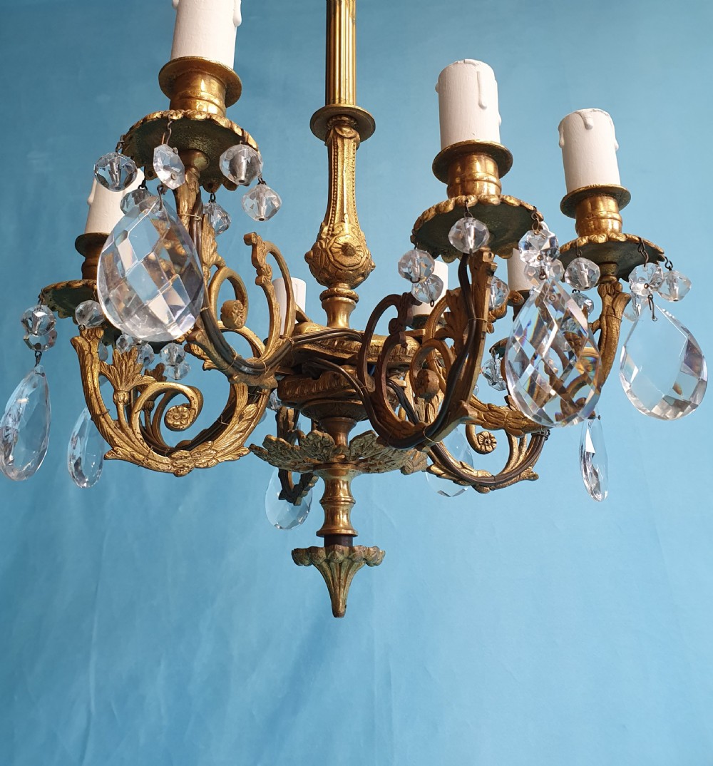 An eight-arm brass ceiling chandelier featuring candle-effect light fittings and suspended crystal glass drops. View VII