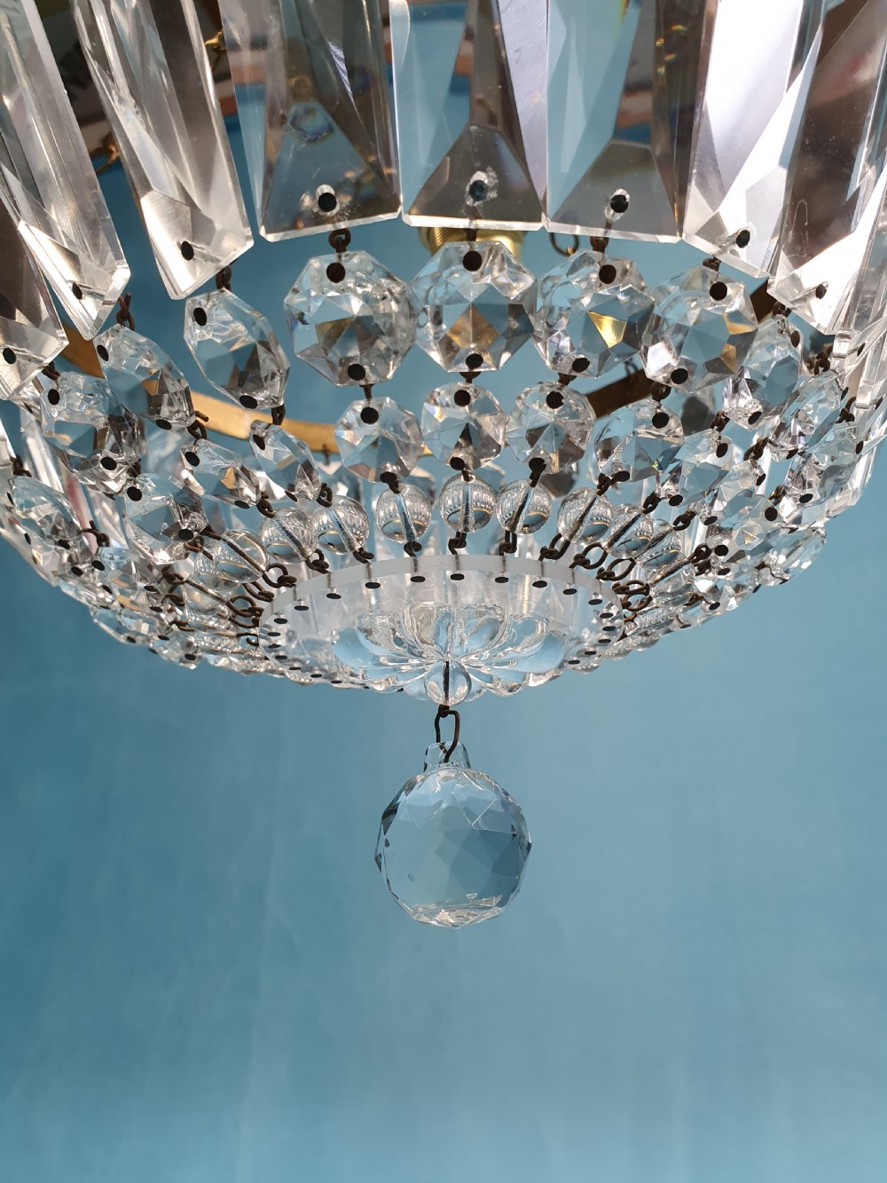An early 20th century ceiling chandelier featuring a circular brass frame with suspended cut crystal prisms forming a hemispherical bag structure. View II