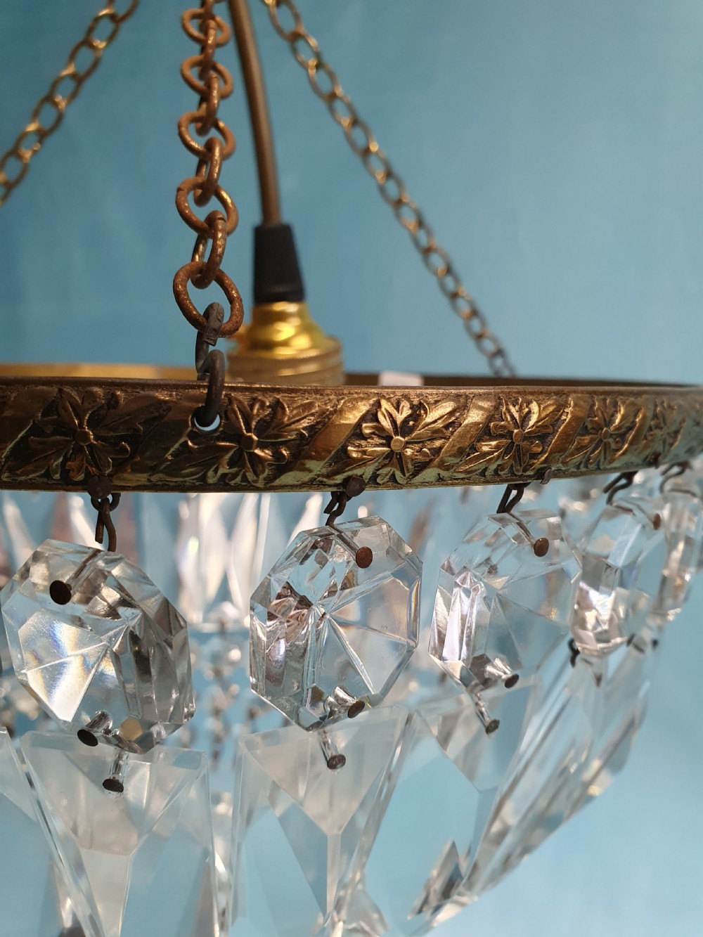 An early 20th century ceiling chandelier featuring a circular brass frame with suspended cut crystal prisms forming a hemispherical bag structure. View III