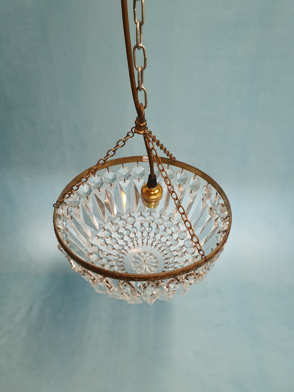 An early 20th century ceiling chandelier featuring a circular brass frame with suspended cut crystal prisms forming a hemispherical bag structure. View V