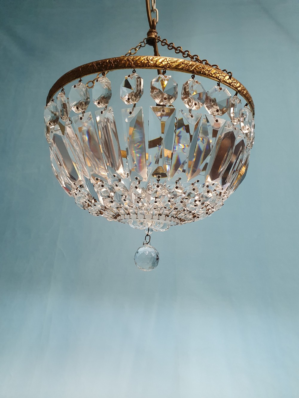 An early 20th century ceiling chandelier featuring a circular brass frame with suspended cut crystal prisms forming a hemispherical bag structure. View VII