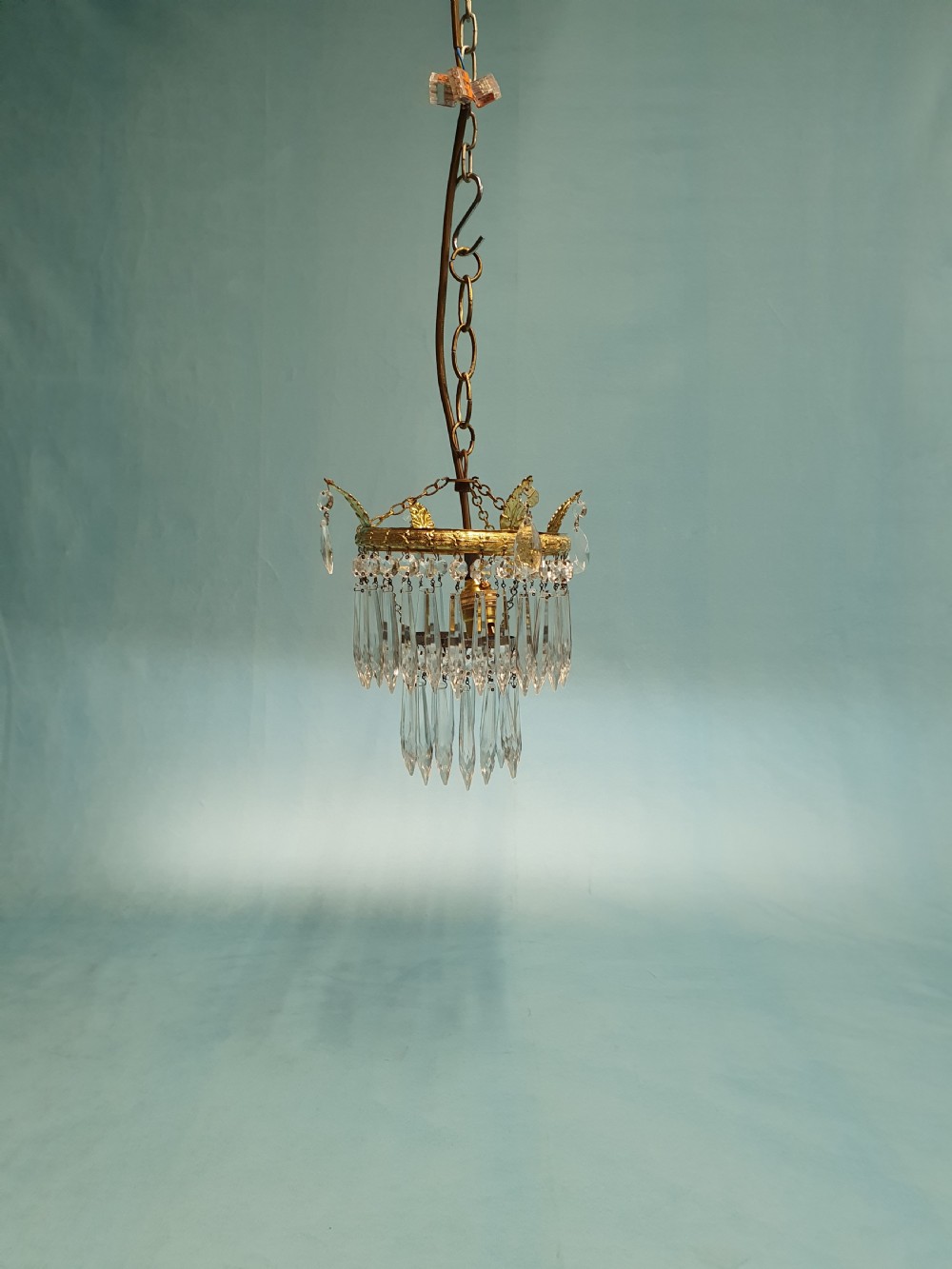 An early 20th-century gilt brass and cut glass crystal spike pendant chandelier with cascading tiers of pointed droplets.