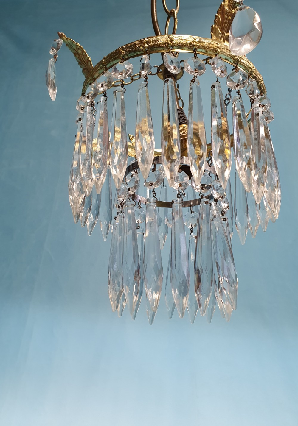 An early 20th-century gilt brass and cut glass crystal spike pendant chandelier with cascading tiers of pointed droplets. View V