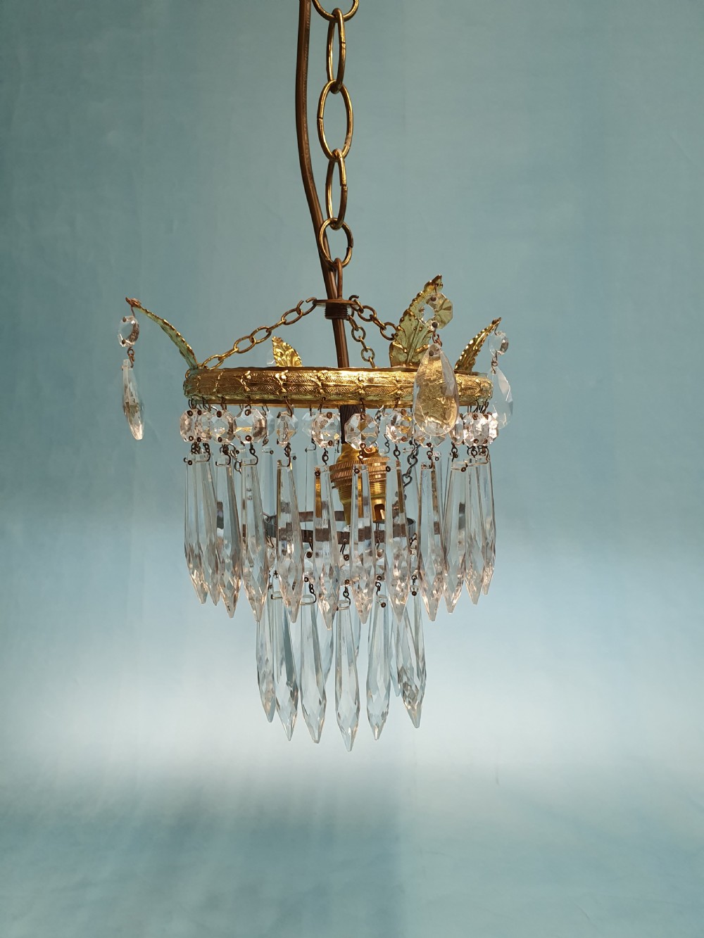 An early 20th-century gilt brass and cut glass crystal spike pendant chandelier with cascading tiers of pointed droplets. View VII