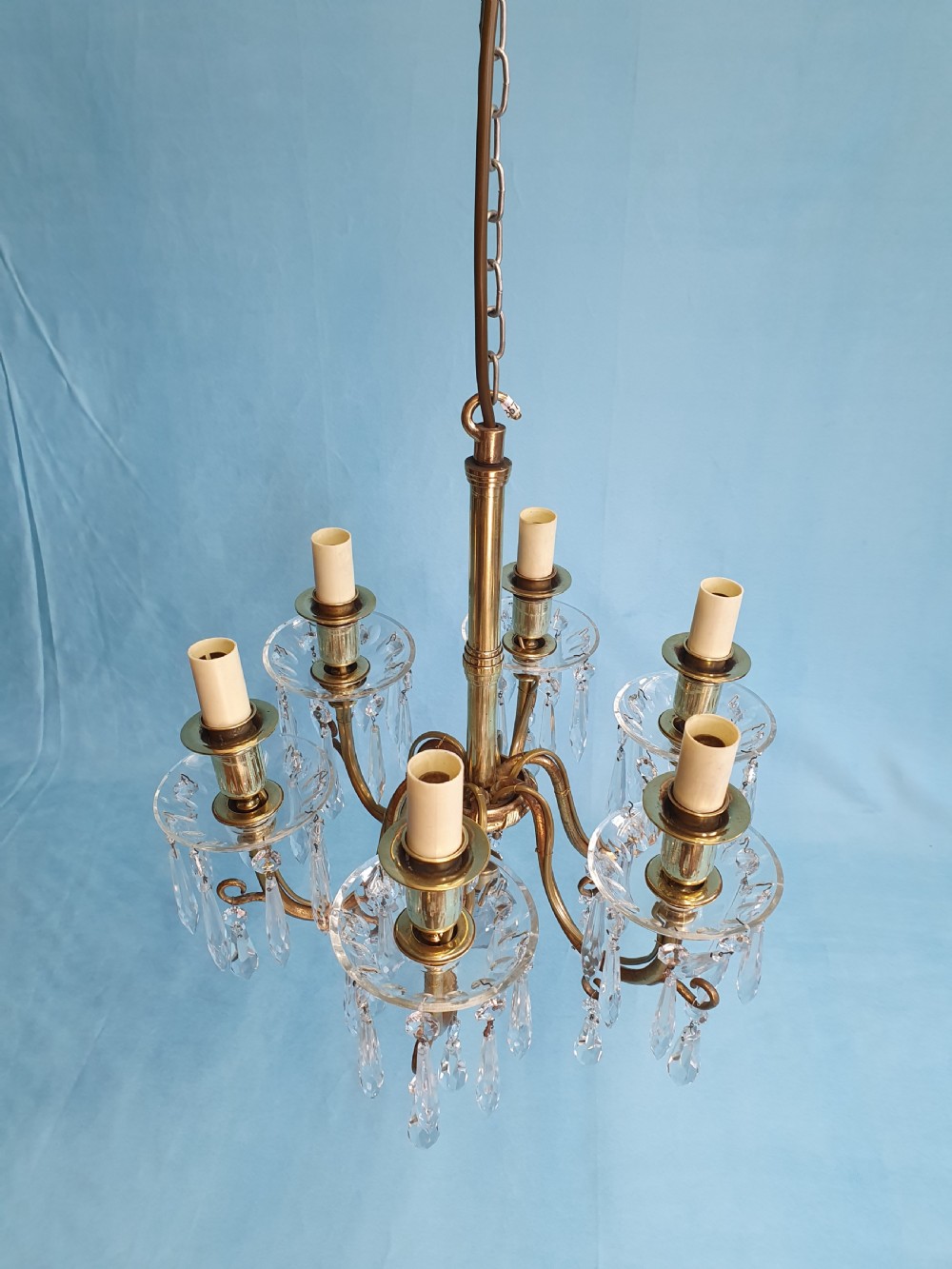 A small six-arm brass chandelier featuring glass drip pans, hanging faceted crystal drops, and a central brass stem with a suspension chain. View II
