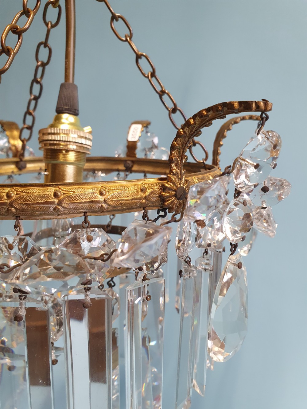An early 20th-century antique chandelier featuring a circular brass frame decorated with hanging crystal swags and long vertical crystal prisms. View VIII