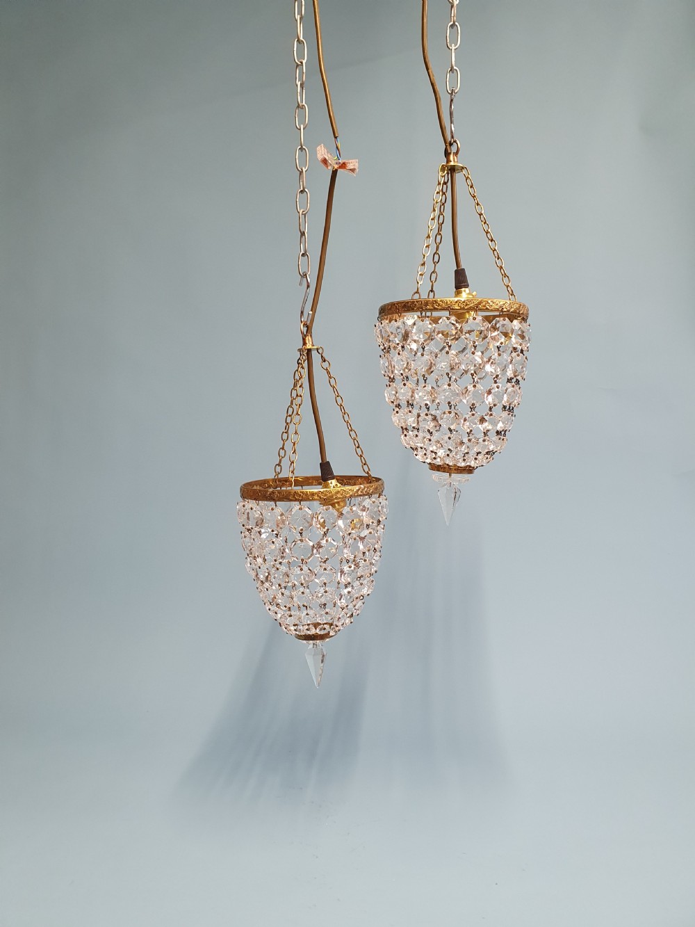 A pair of small early 20th-century bag chandeliers featuring brass rims decorated with linked glass crystal beads and lower teardrop prisms.