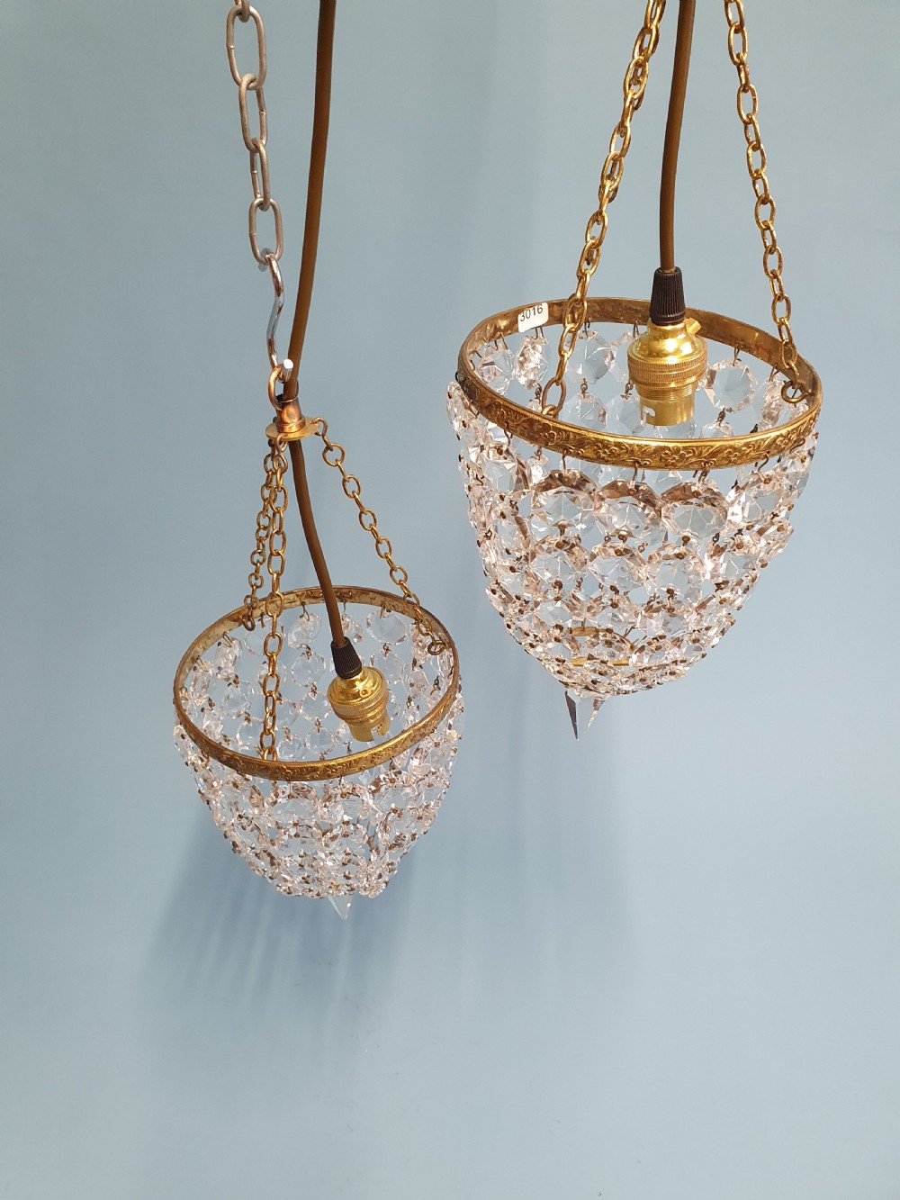 A pair of small early 20th-century bag chandeliers featuring brass rims decorated with linked glass crystal beads and lower teardrop prisms. View IV