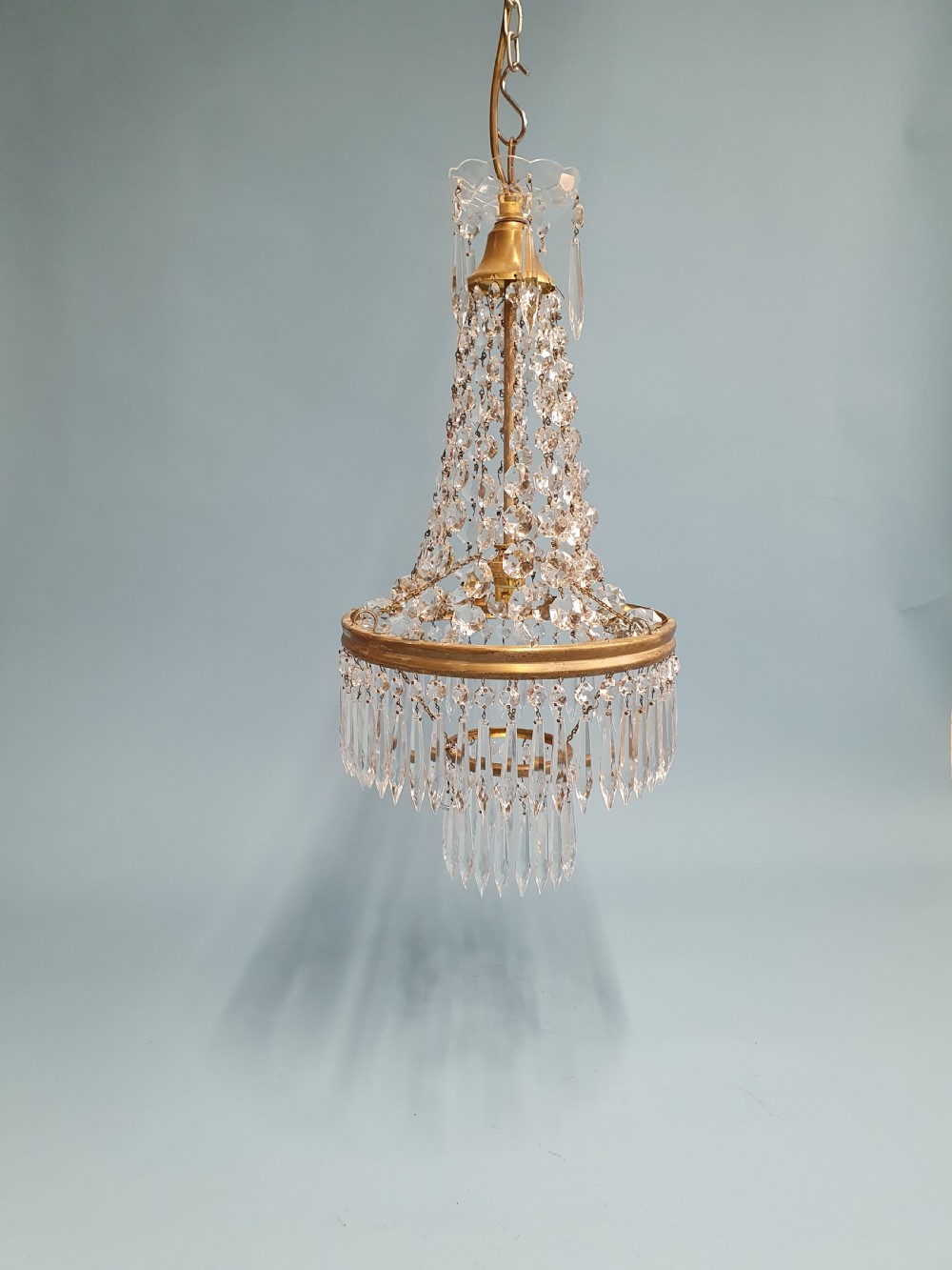 An early 20th-century ceiling chandelier featuring a tent of cascading crystal beads ending at a brass ring hung with vertical crystal spike drops.