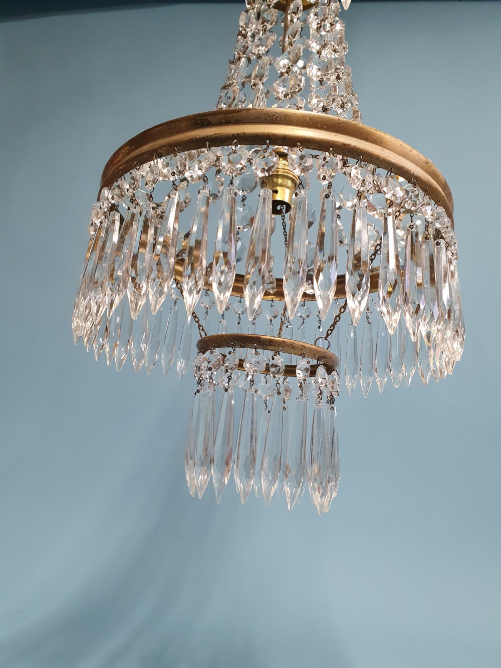 An early 20th-century ceiling chandelier featuring a tent of cascading crystal beads ending at a brass ring hung with vertical crystal spike drops. View V