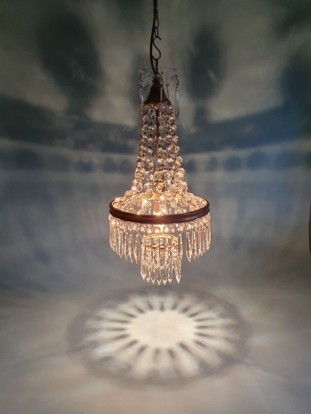 An early 20th-century ceiling chandelier featuring a tent of cascading crystal beads ending at a brass ring hung with vertical crystal spike drops. View VI
