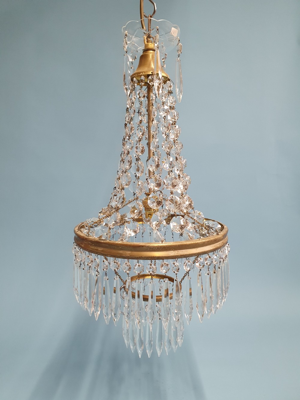 An early 20th-century ceiling chandelier featuring a tent of cascading crystal beads ending at a brass ring hung with vertical crystal spike drops. View VII