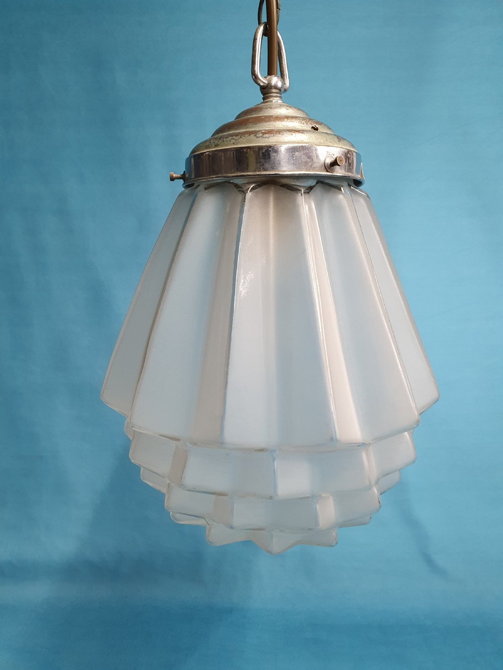 A frosted white Art Deco glass pendant light shade featuring a geometric stepped design suspended by a metal chain. View II