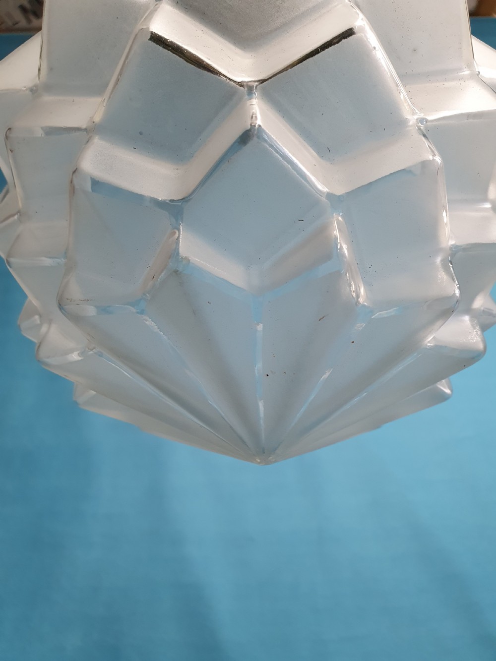 A frosted white Art Deco glass pendant light shade featuring a geometric stepped design suspended by a metal chain. View IV