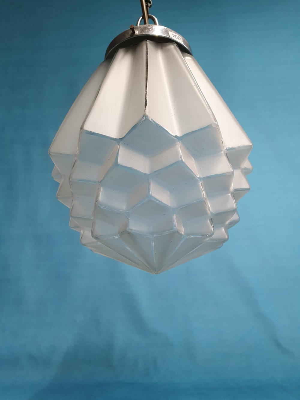 A frosted white Art Deco glass pendant light shade featuring a geometric stepped design suspended by a metal chain. View V