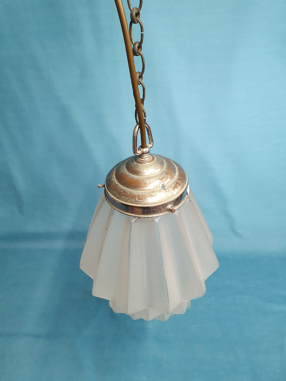 A frosted white Art Deco glass pendant light shade featuring a geometric stepped design suspended by a metal chain. View VI
