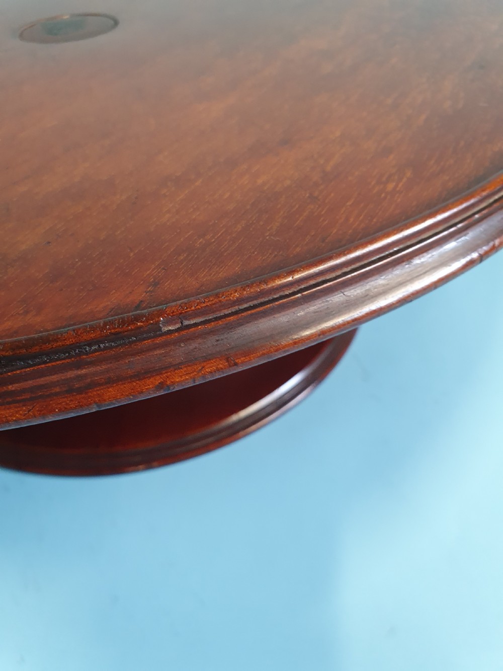 A circular Edwardian mahogany lazy Susan with a raised moulded edge resting on a central turned pedestal base. View III