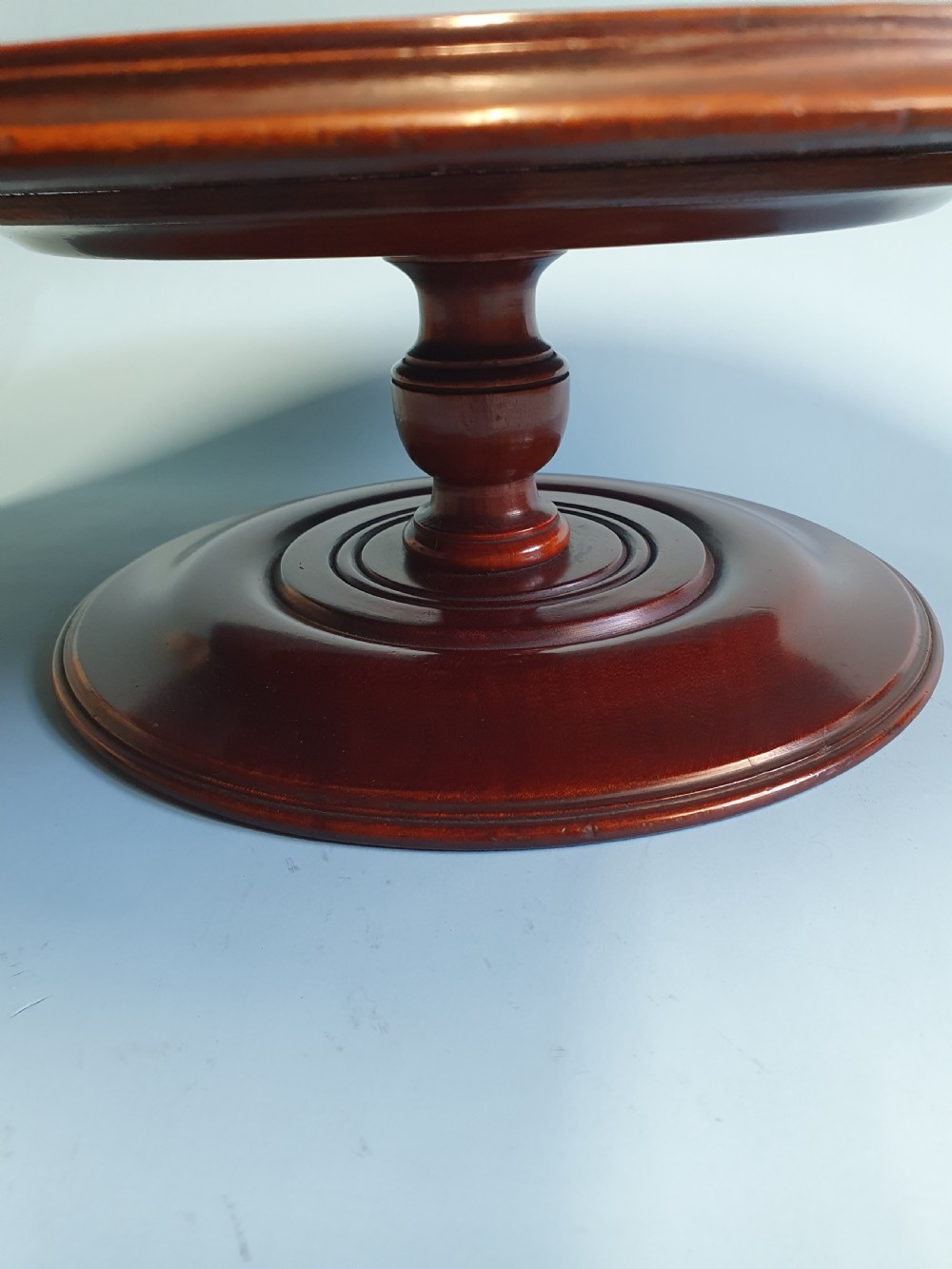 A circular Edwardian mahogany lazy Susan with a raised moulded edge resting on a central turned pedestal base. View VI