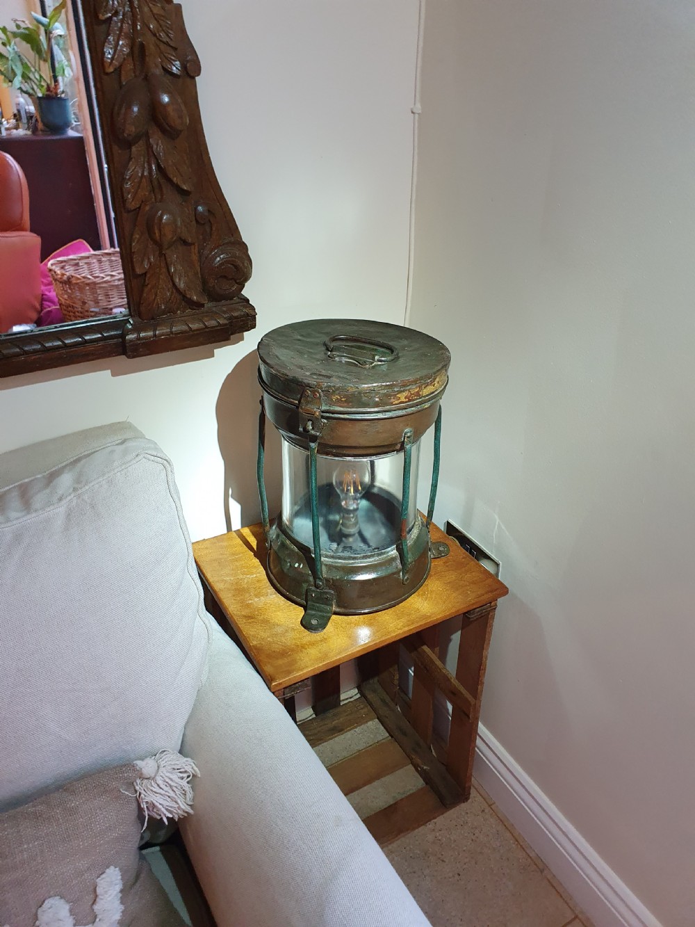 A cylindrical antique copper ship lantern featuring a verdigris patina, clear glass lens, protective metal cage, and top carrying handle.