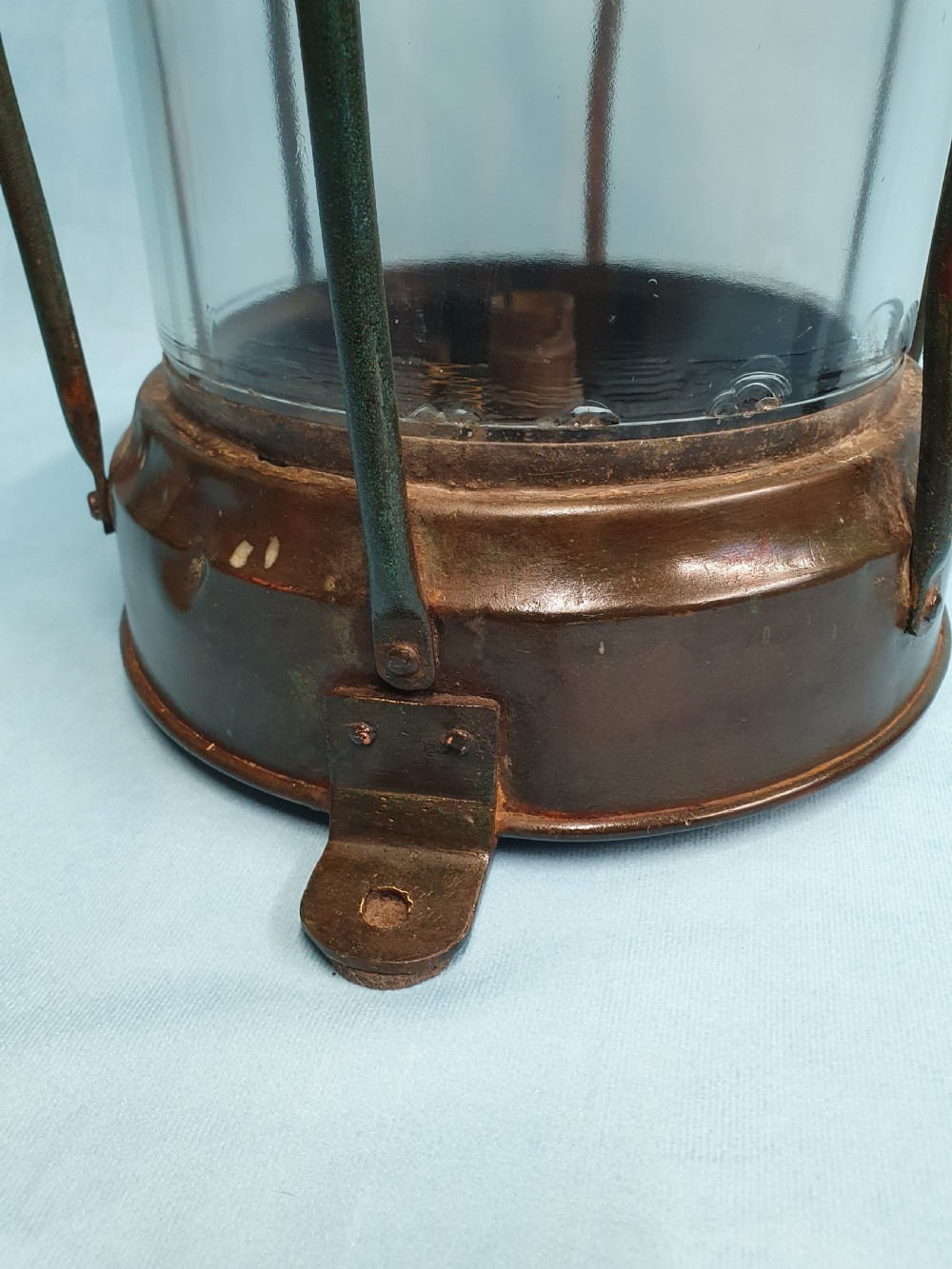 A cylindrical antique copper ship lantern featuring a verdigris patina, clear glass lens, protective metal cage, and top carrying handle. View II