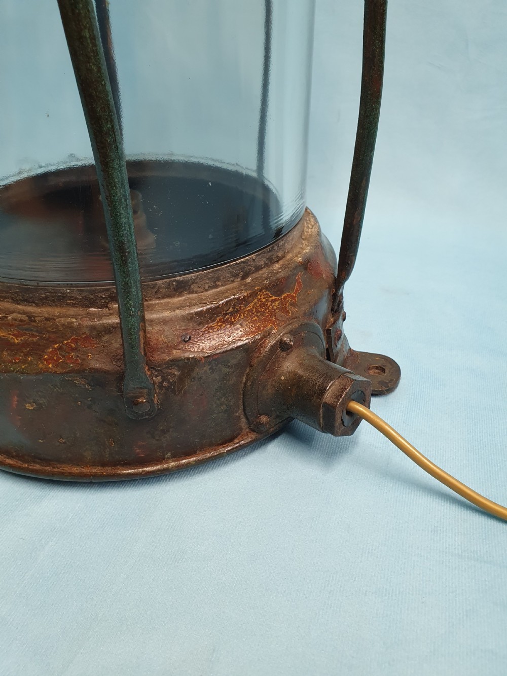 A cylindrical antique copper ship lantern featuring a verdigris patina, clear glass lens, protective metal cage, and top carrying handle. View VIII