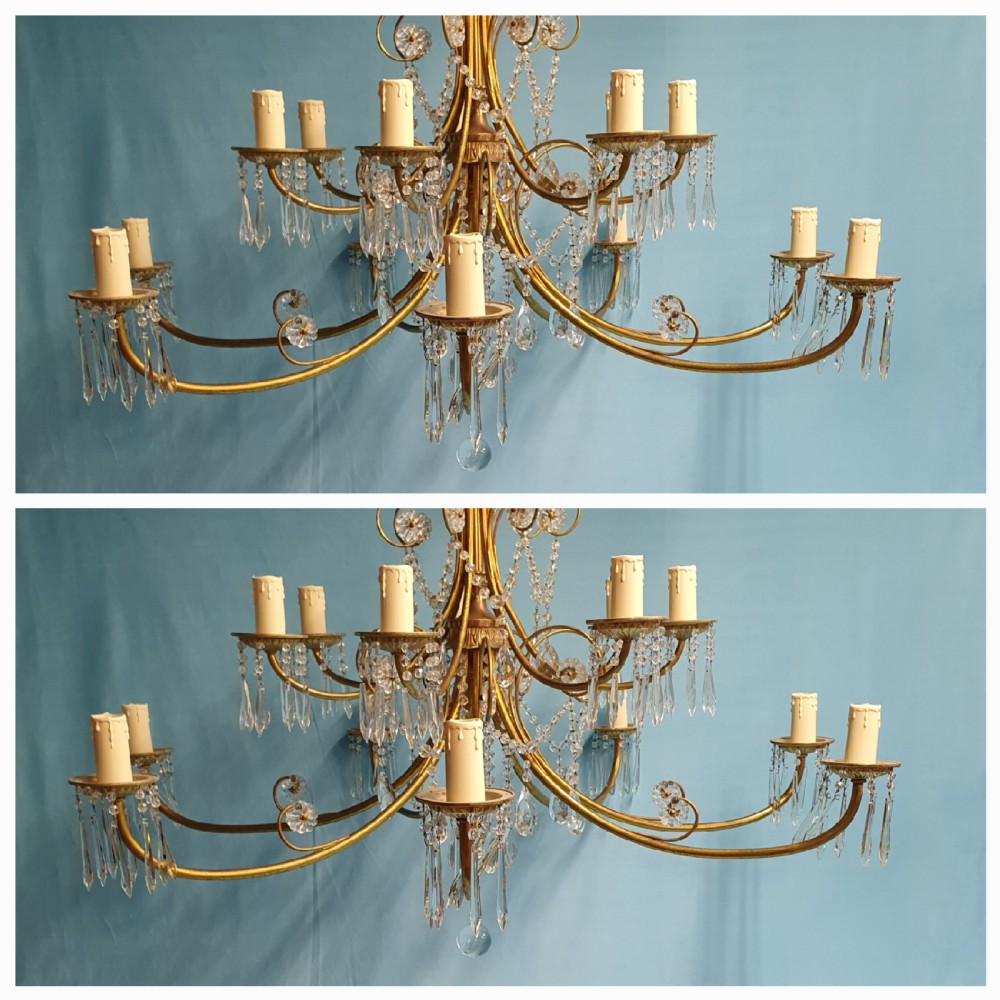 A pair of early 20th-century brass two-tier chandeliers decorated with cut glass crystal prisms, bead garlands, and candle sleeves. View IV