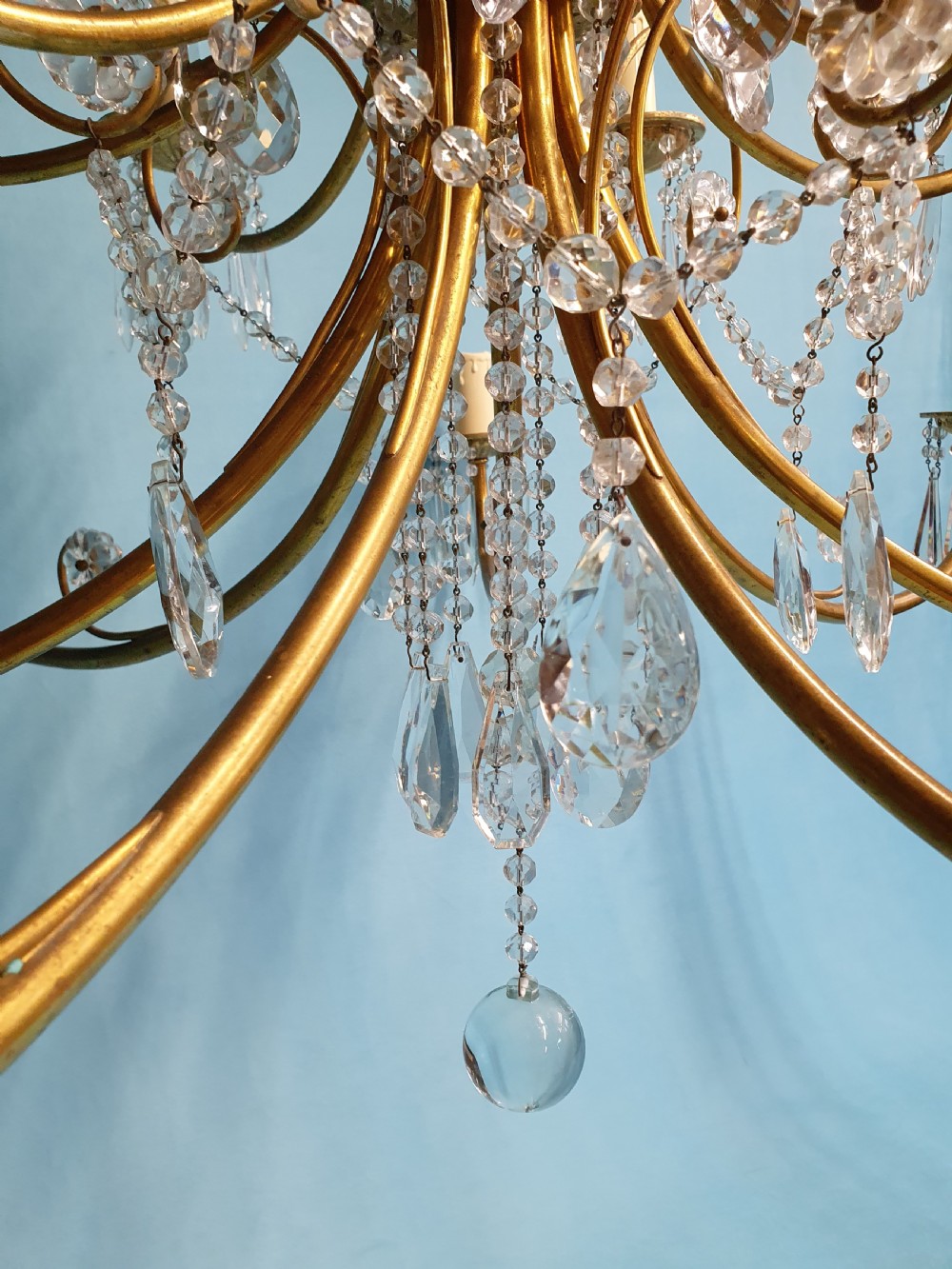 A pair of early 20th-century brass two-tier chandeliers decorated with cut glass crystal prisms, bead garlands, and candle sleeves. View V