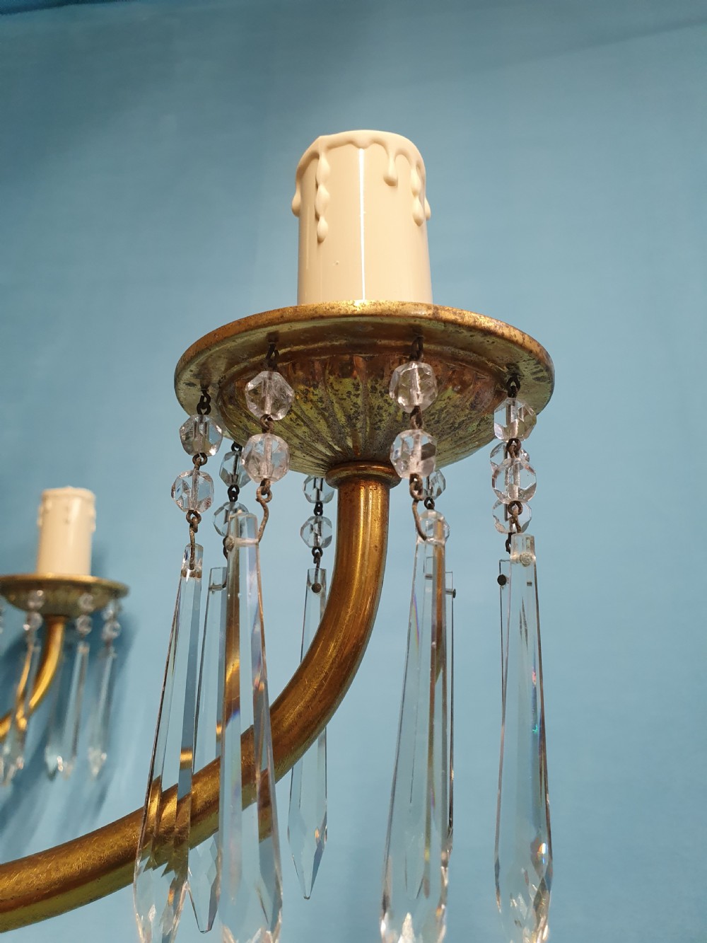 A pair of early 20th-century brass two-tier chandeliers decorated with cut glass crystal prisms, bead garlands, and candle sleeves. View VI
