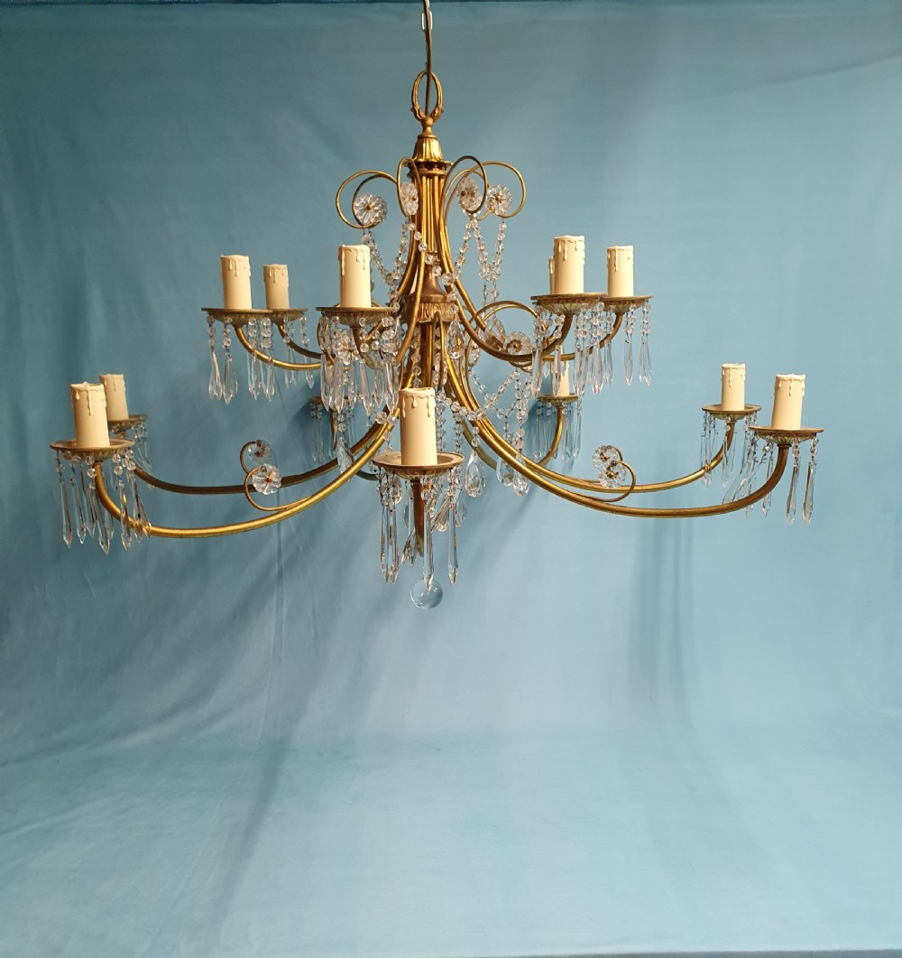 A pair of early 20th-century brass two-tier chandeliers decorated with cut glass crystal prisms, bead garlands, and candle sleeves. View VII