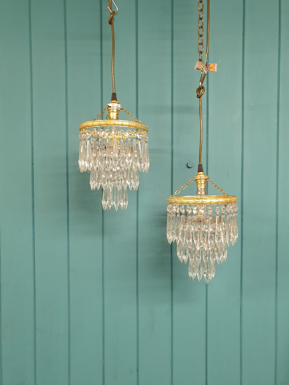 A pair of early 20th century light fixtures featuring gilt brass circular rings with suspended concentric tiers of pointed clear crystal glass prisms.