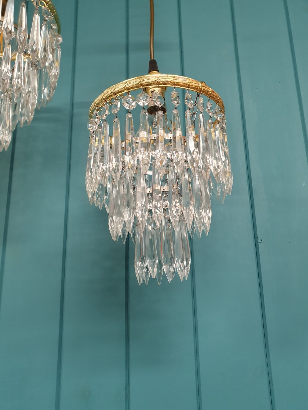 A pair of early 20th century light fixtures featuring gilt brass circular rings with suspended concentric tiers of pointed clear crystal glass prisms. View III