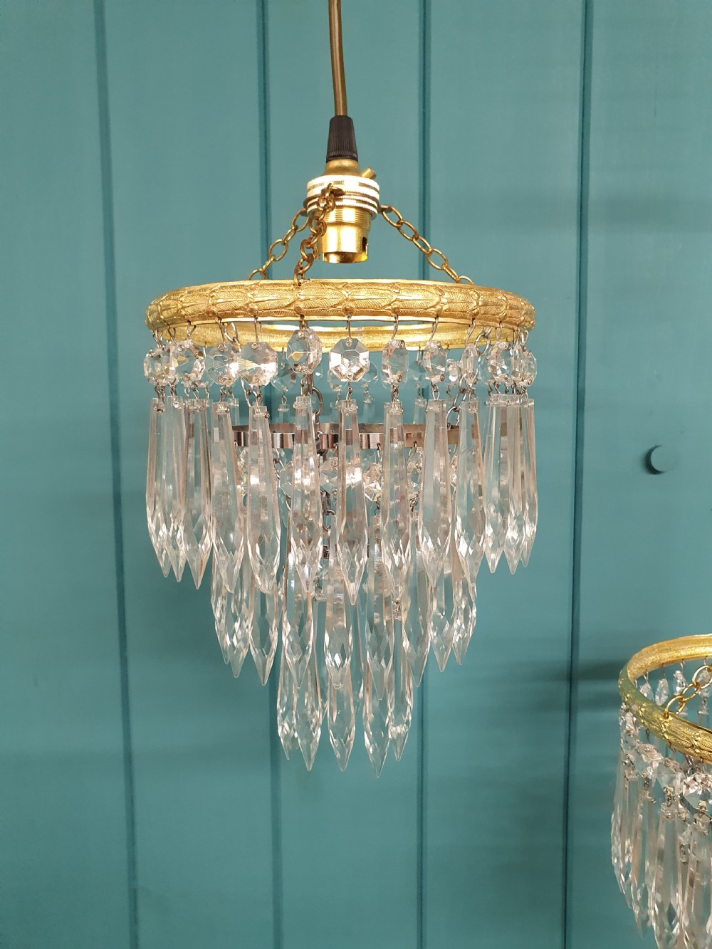 A pair of early 20th century light fixtures featuring gilt brass circular rings with suspended concentric tiers of pointed clear crystal glass prisms. View V