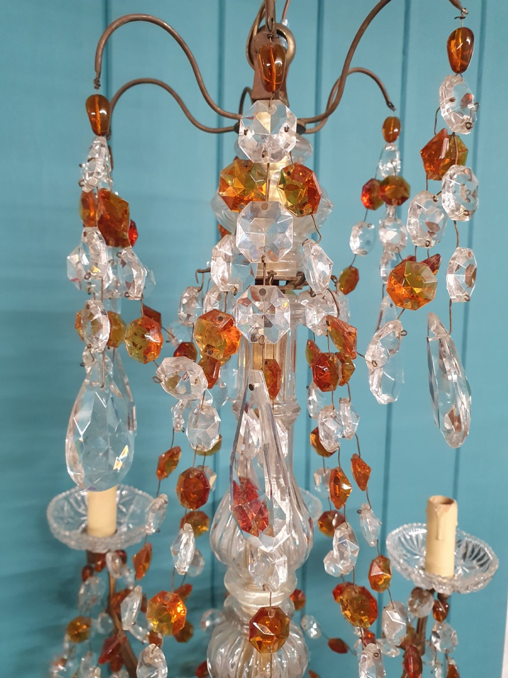 An early 20th century French brass chandelier featuring clear cut crystal droplets, amber glass beads, and candle-sleeve light fittings. View II