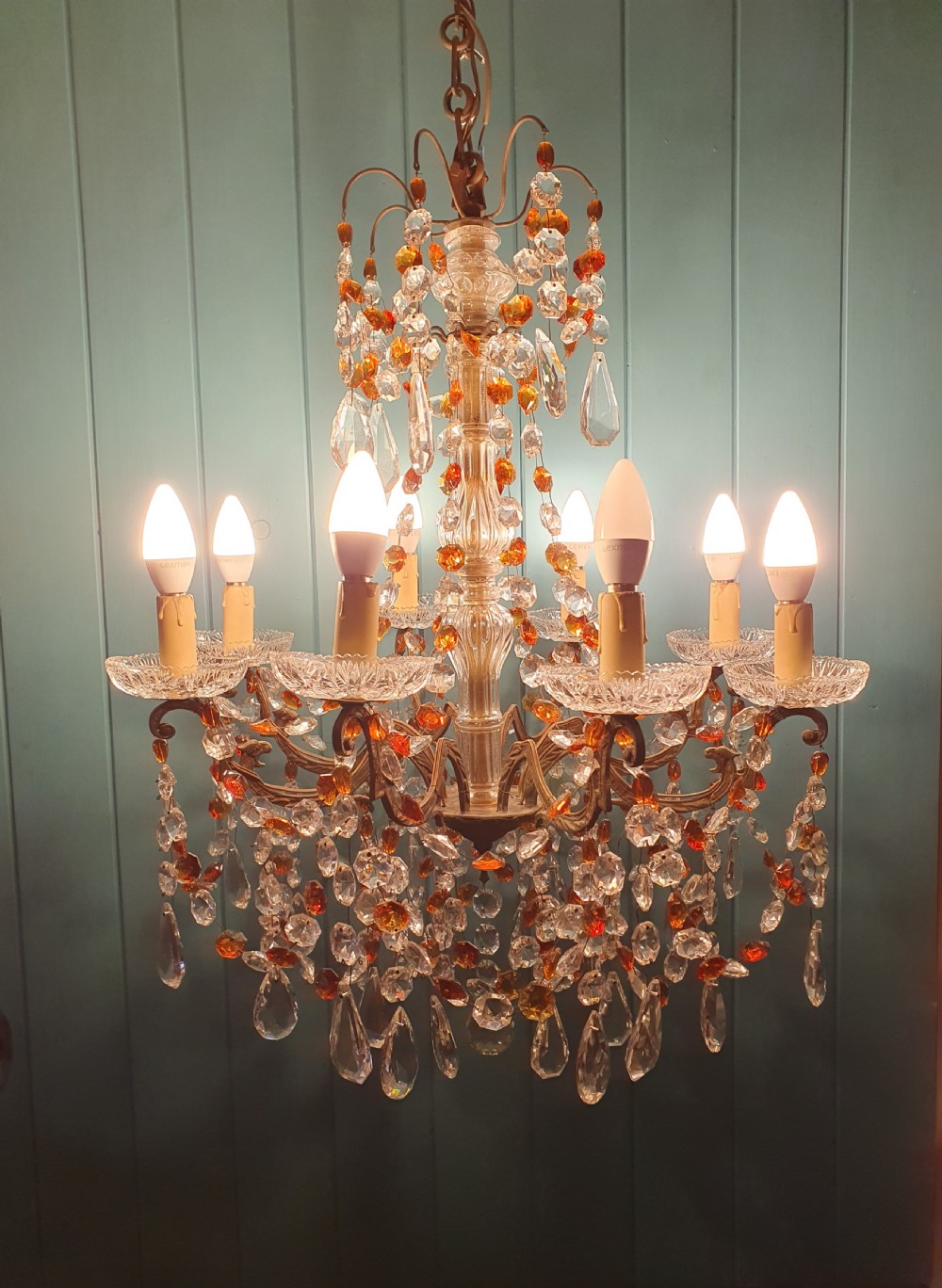 An early 20th century French brass chandelier featuring clear cut crystal droplets, amber glass beads, and candle-sleeve light fittings. View III
