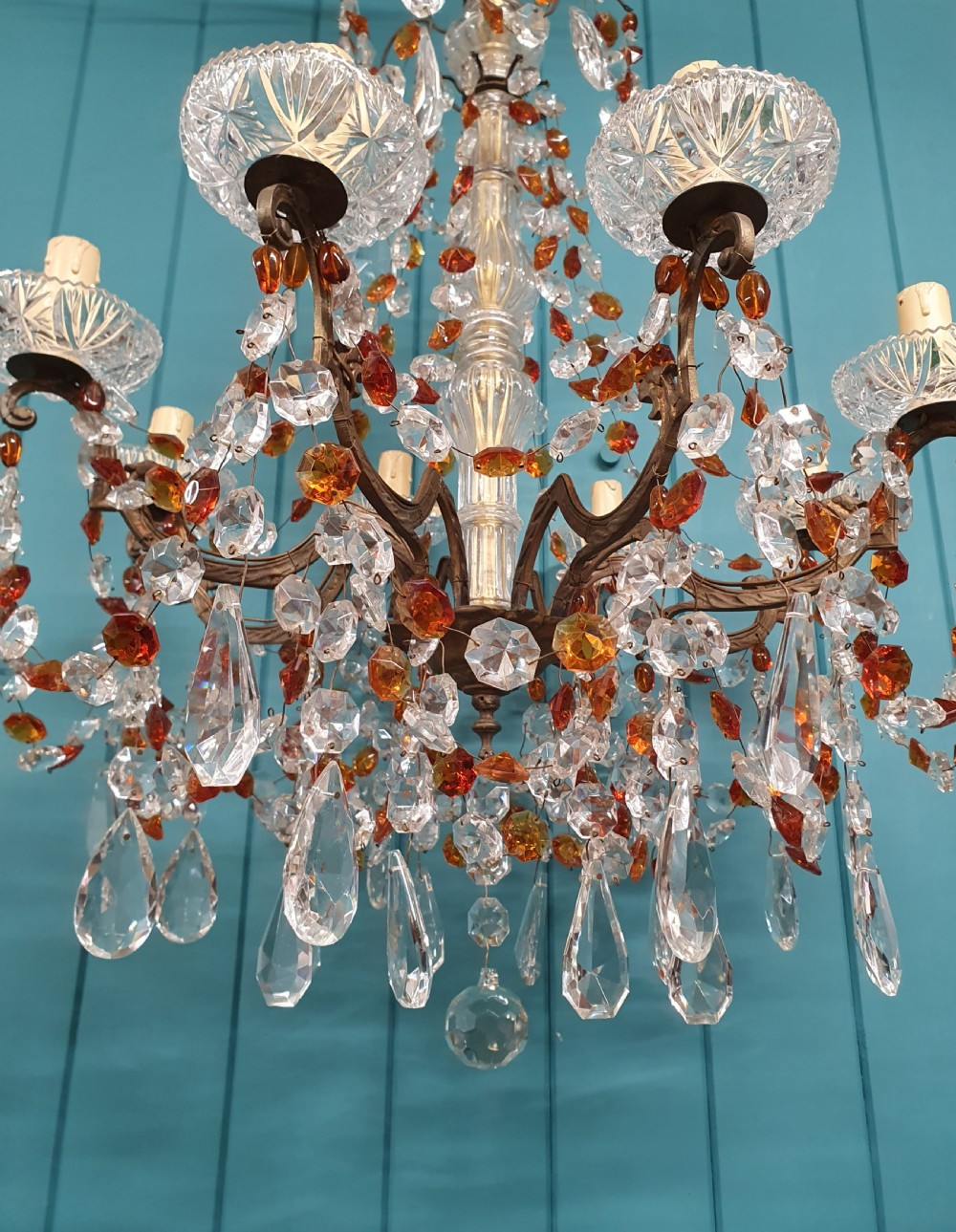 An early 20th century French brass chandelier featuring clear cut crystal droplets, amber glass beads, and candle-sleeve light fittings. View V