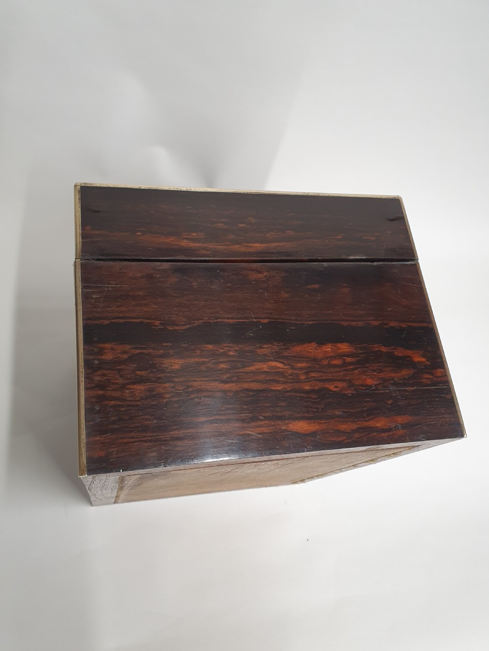 A Victorian dark brown coromandel wood dressing box with fine brass stringing, brass edging, and a central brass shield cartouche. View V