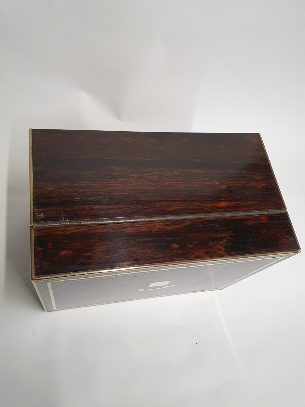 A Victorian dark brown coromandel wood dressing box with fine brass stringing, brass edging, and a central brass shield cartouche. View VI