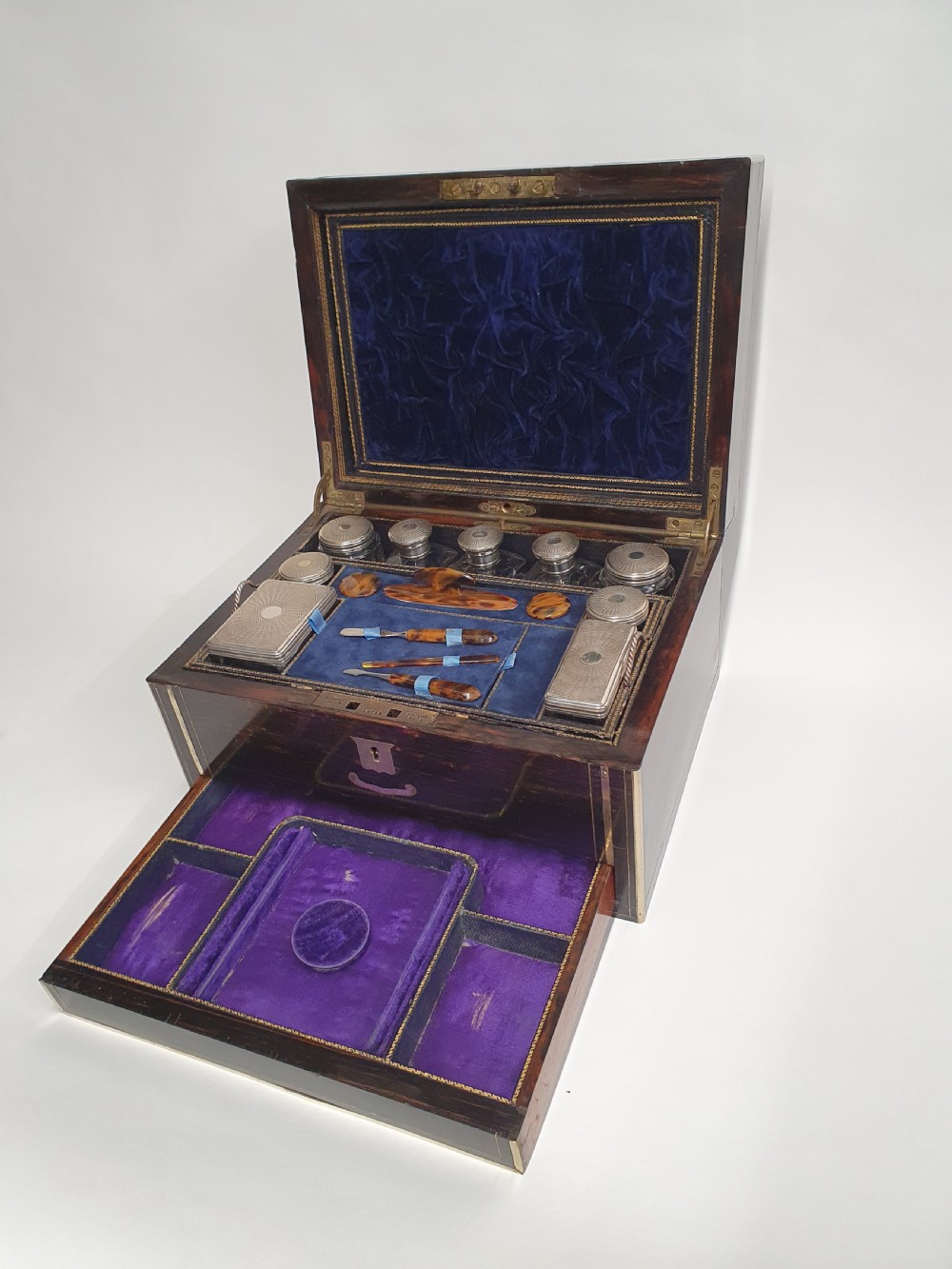 A Victorian dark brown coromandel wood dressing box with fine brass stringing, brass edging, and a central brass shield cartouche. View XI