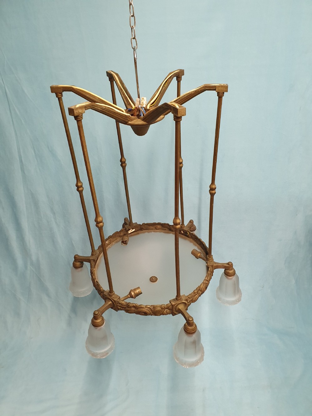 A pair of early 20th-century brass pendant lights featuring tall angular cage frames supporting ornate floral band bases with multiple suspended frosted glass shades. View II