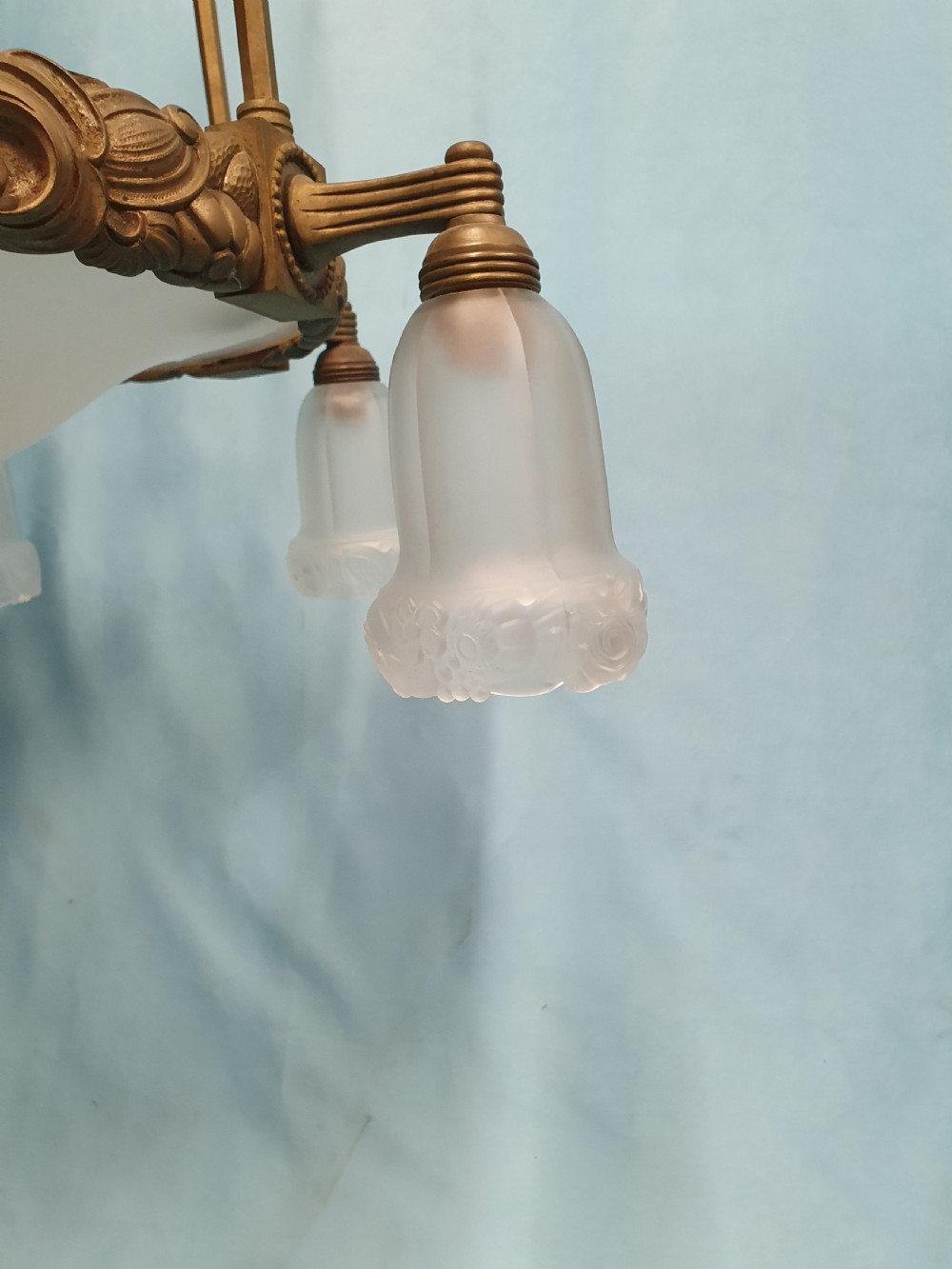 A pair of early 20th-century brass pendant lights featuring tall angular cage frames supporting ornate floral band bases with multiple suspended frosted glass shades. View IV